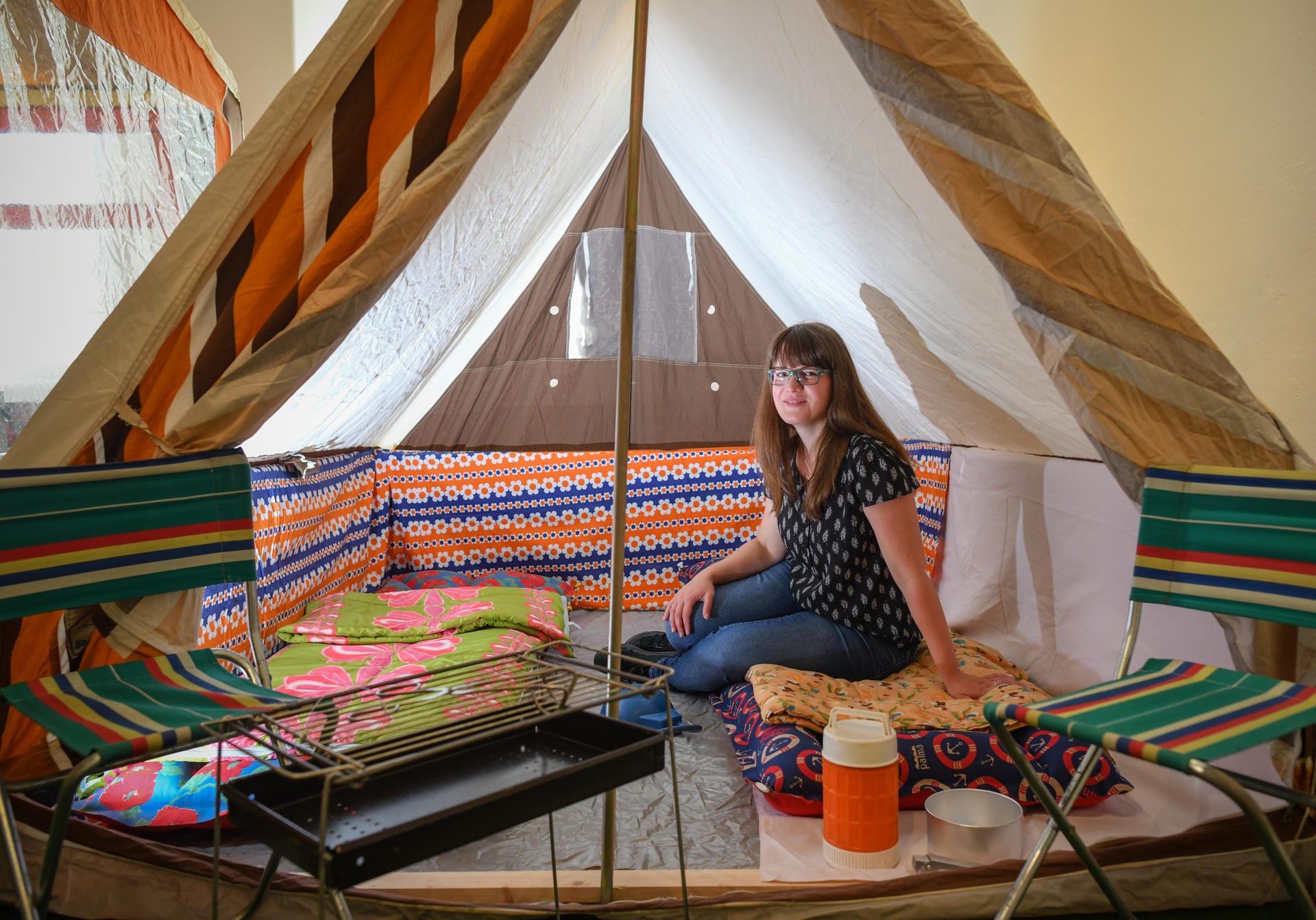 Jenny Linke, Marketingmitarbeiterin des Landkreises Oberspreewald-Lausitz, sitzt auf in einem Zelt in der Ausstellung.