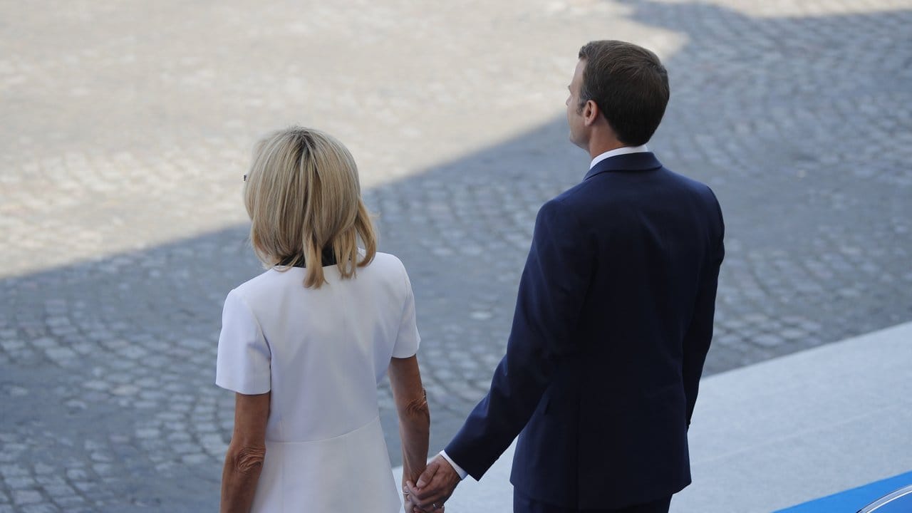 Emmanuel Macron, Präsident von Frankreich, steht Hand in Hand neben seiner Ehefrau Brigitte Macron.
