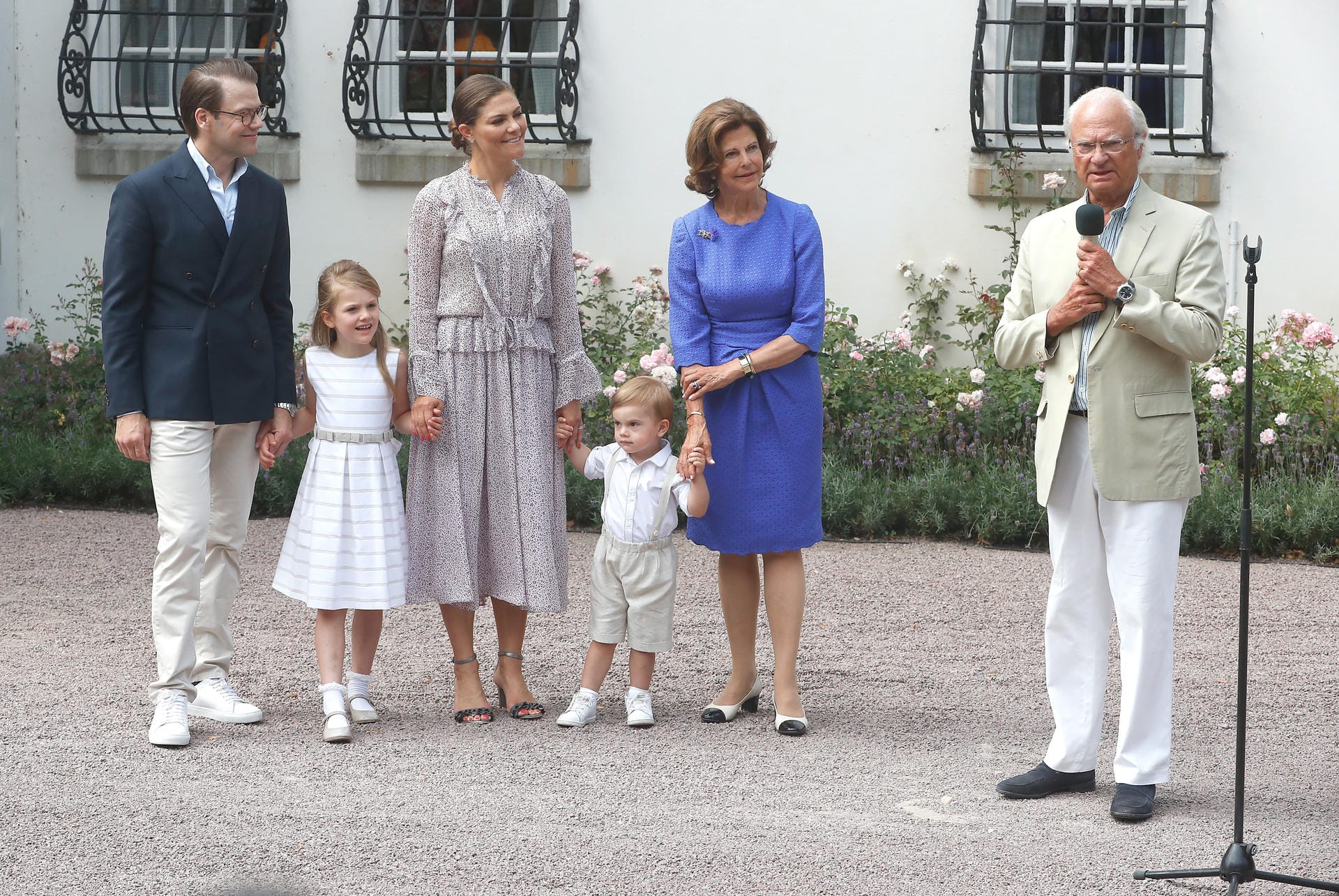 Auf das Posieren für die Fotografen hatte der zweijährige Prinz offenbar auch keine Lust. Während Daniel und Victoria mit Estelle in der Mitte ein ruhiges Bild abgaben, zog Oscar am Arm von Oma Köngin Silvia. König Carl Gustaf ergreift derweil das Wort.
