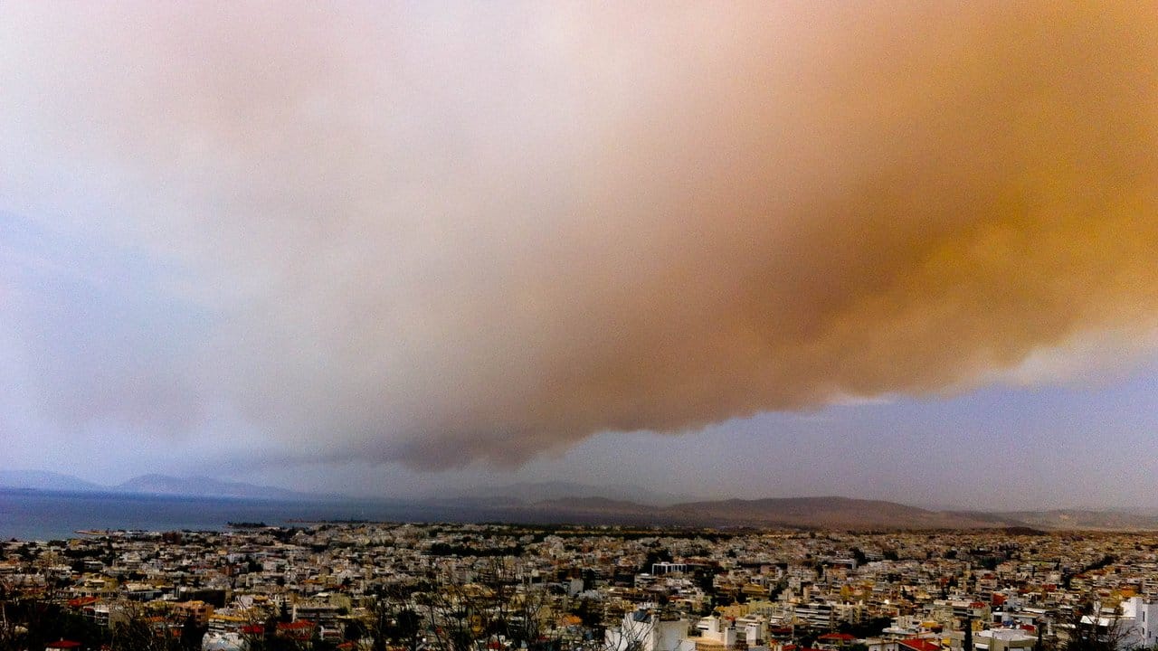 Eine Rauchwolke färbt Teile des Himmels über Athen orange.