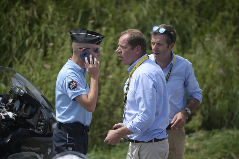 Tour-Direktor Christian Prudhomme tauscht sich mit der Polizei aus. Er ließ das Rennen vorsorglich unterbrechen und erst zehn Minuten später wieder fortsetzen.