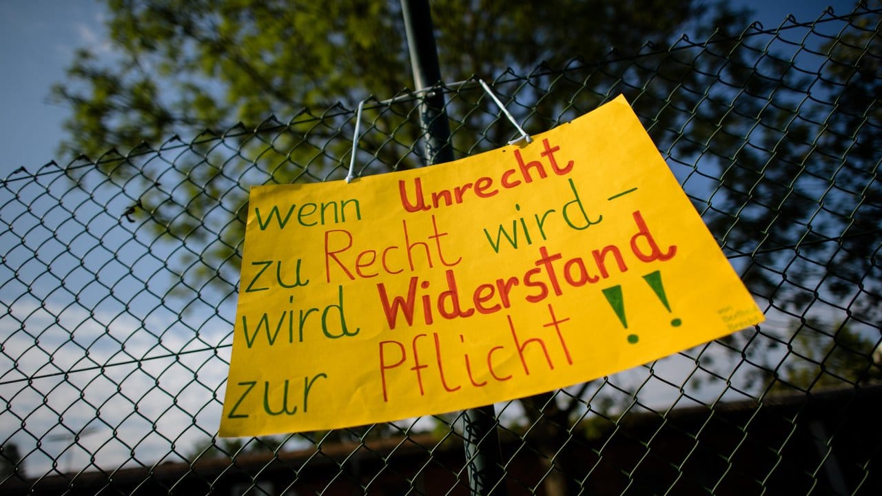 Ein Protestplakat ist am Rande der Gründungsfeier des Landesamtes für Asyl im Transitzentrum Manching angebracht.