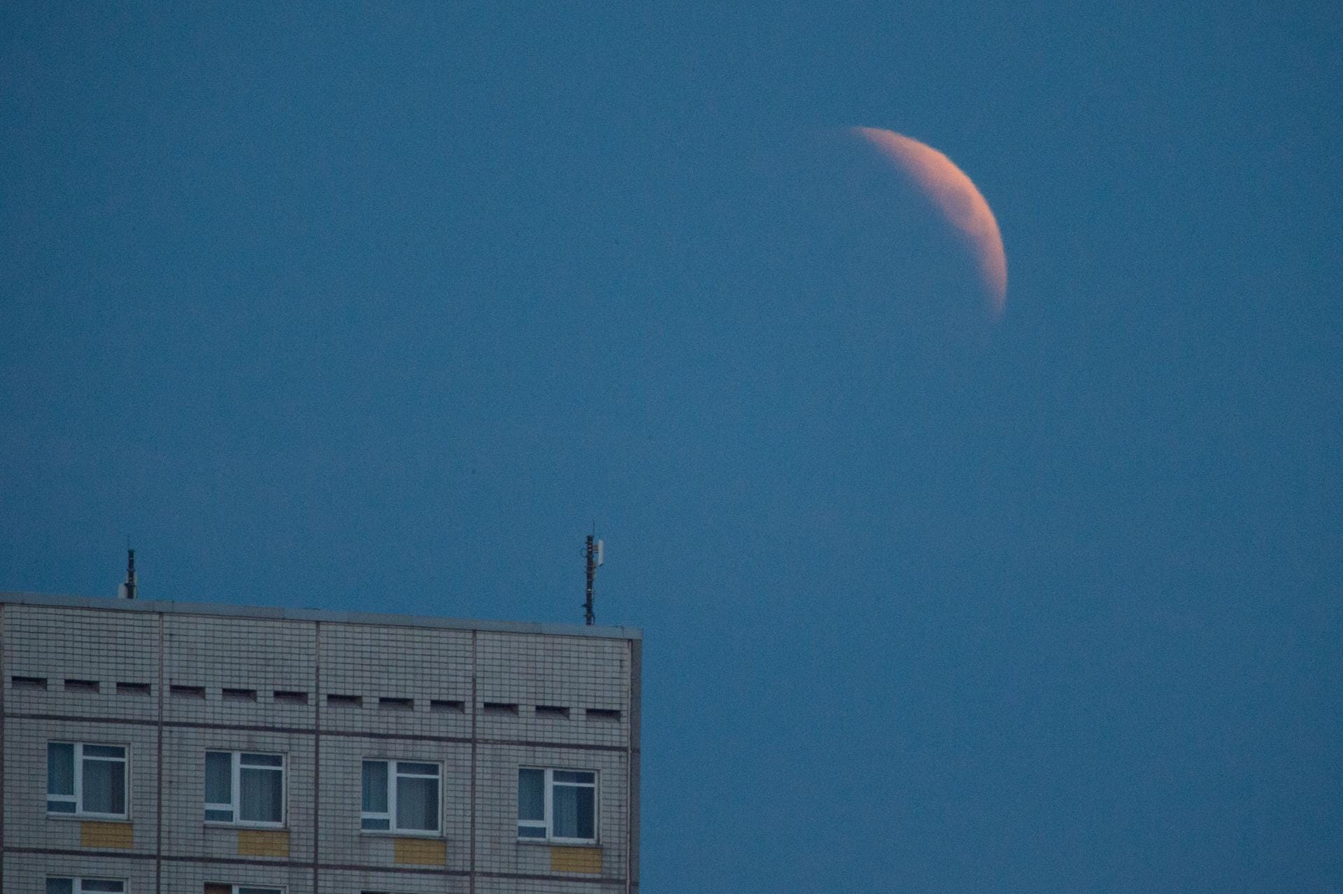 Die Mondfinsternis beginnt: Der aufgehende Mond ist hinter einem Hotelgebäude in Dresden zu sehen.