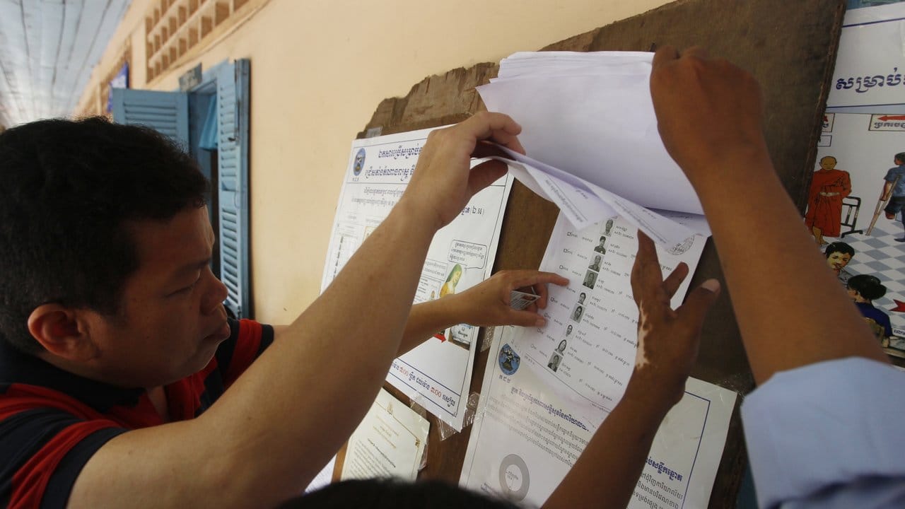 Kambodschanische Wähler schauen sich Registrierungslisten an, bevor sie bei der Parlamentswahl ihre Stimme abgeben.
