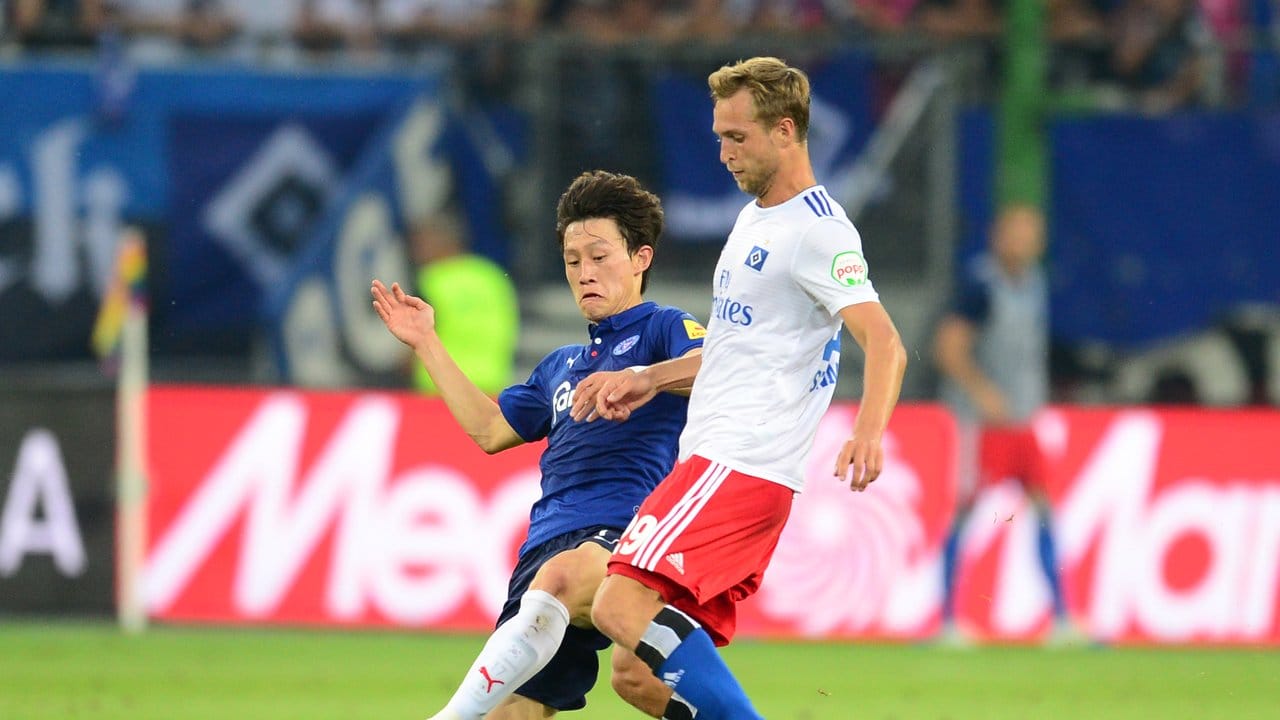 Kiels Jae-song Lee (l) und Matti Steinmann vom HSV kämpfen um den Ball.