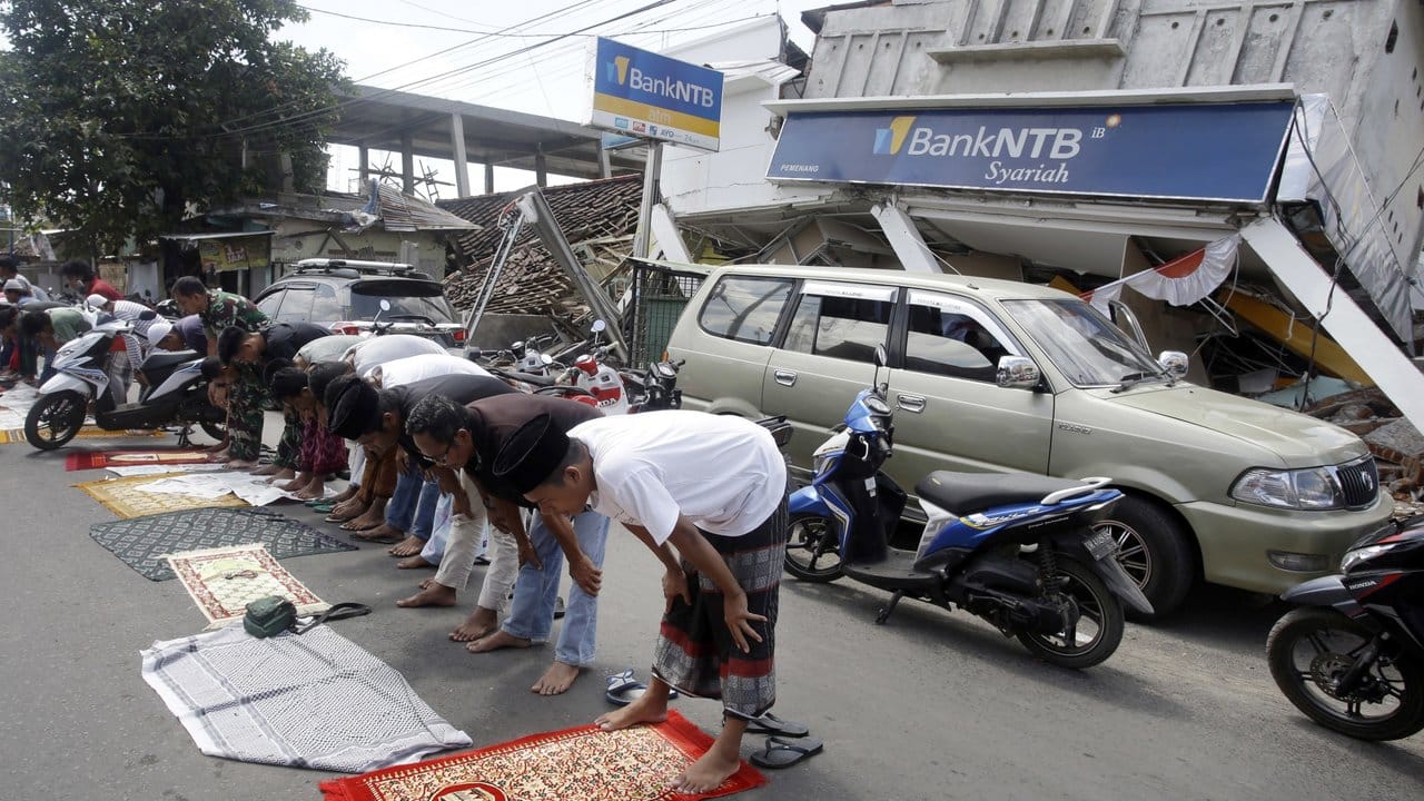 Vor einer eingestürzten Bankfiliale auf Lombok versammeln sich Anwohner zum muslimischen Freitagsgebet.