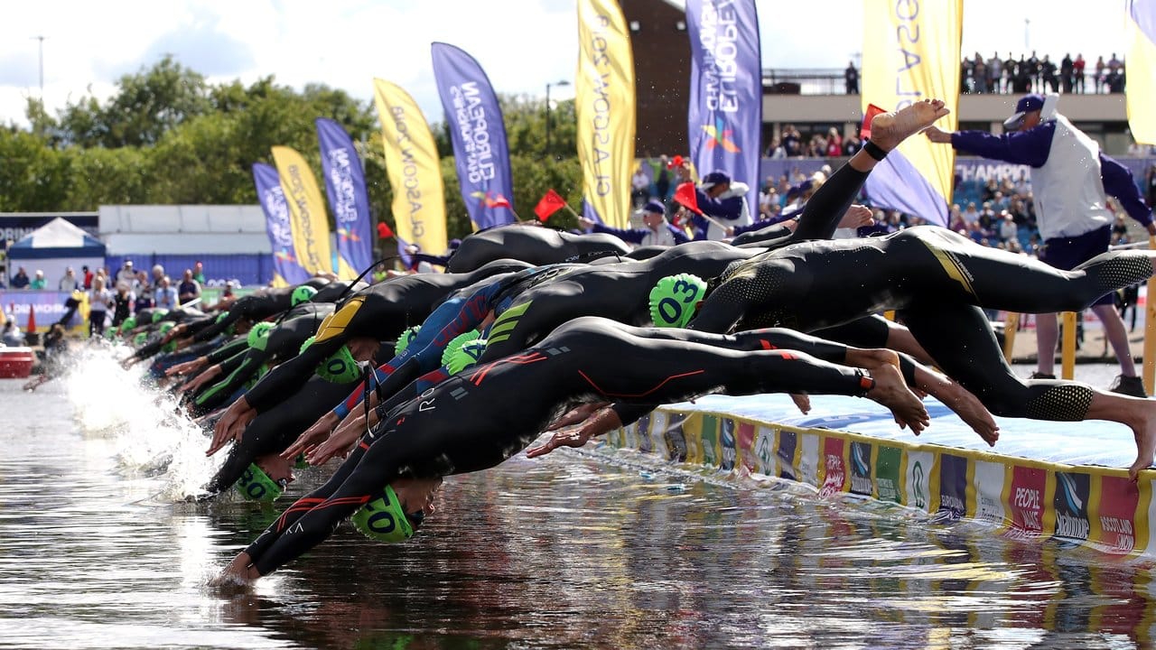Die Teilnehmer des Männer-Triathlons springen beim Start in Glasgow ins Wasser.