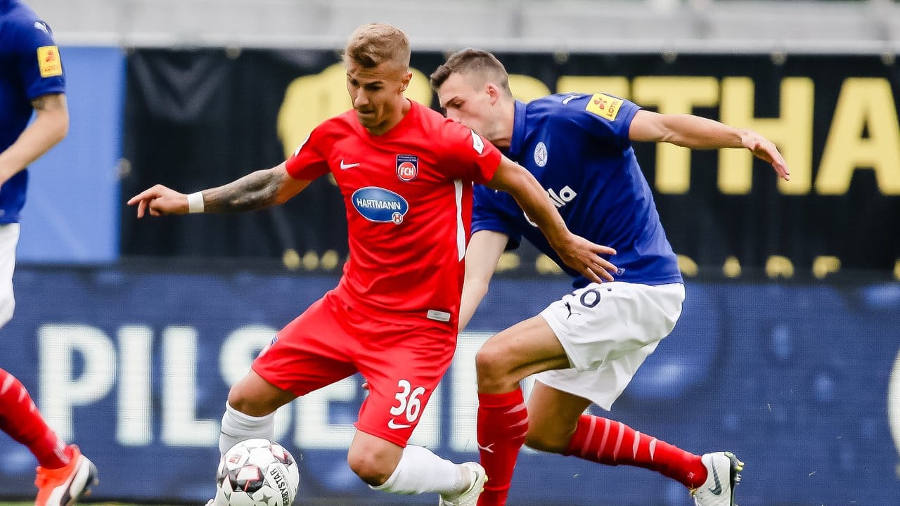 Niklas Dorsch (l) vom FC Heidenheim und der Kieler Jonas Meffert kämpfen um den Ball.