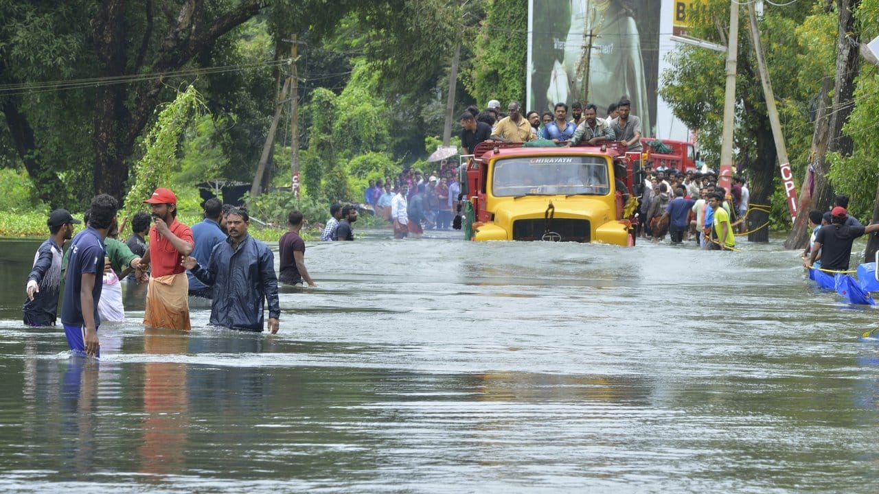 Ein LKW transportiert Menschen auf einer überfluteten Straße.