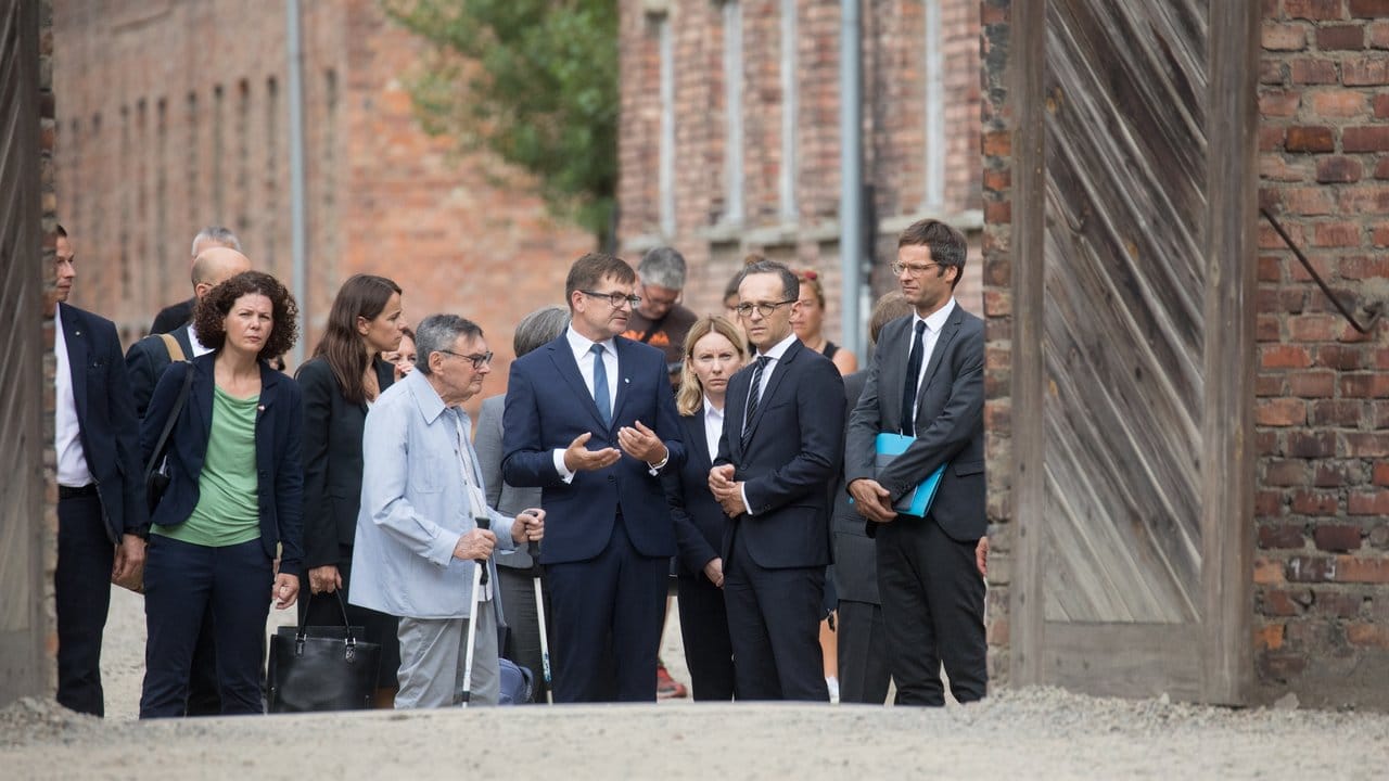 Heiko Maas spricht mit Andrzej Kacorzyk, dem stellvertretenden Direktor der Gedenkstätte Auschwitz-Birkenau, und Marian Turski (mit Krücken), ein ehemaliger Insasse von Auschwitz und Vorsitzender des Jüdischen Historischen Instituts in Warschau.