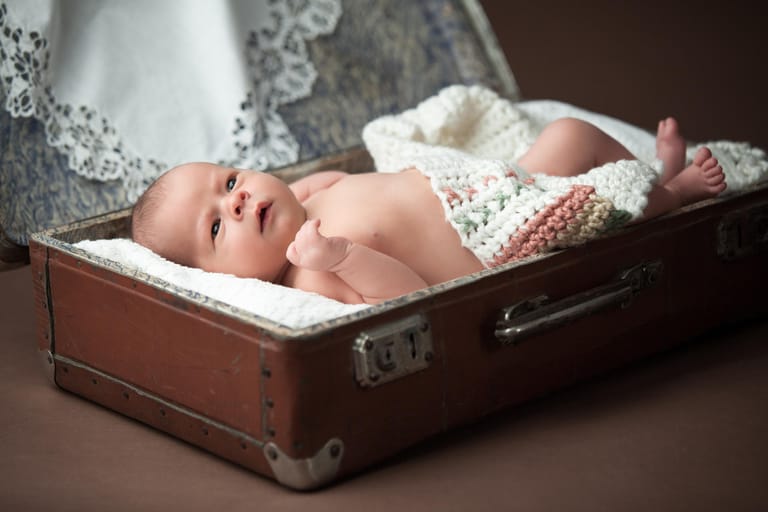 Ein sieben Tage altes Baby liegt in einem Vintage-Koffer. Am besten ist es, wenn ein Newborn-Shooting zwischen dem fünften und dem zehnten Lebenstag stattfindet.