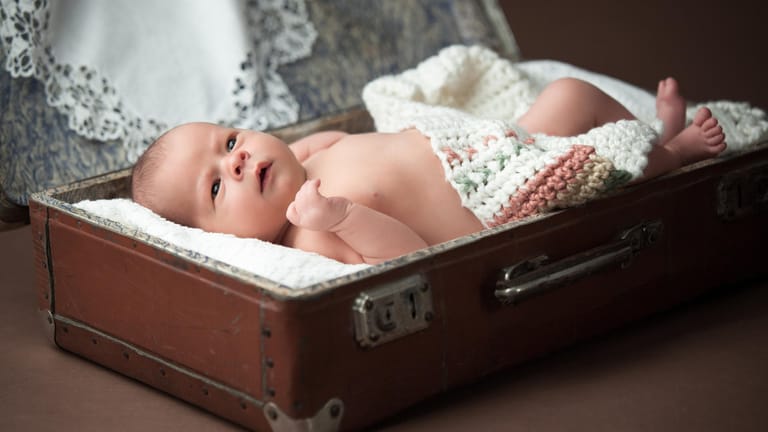 Ein sieben Tage altes Baby liegt in einem Vintage-Koffer. Am besten ist es, wenn ein Newborn-Shooting zwischen dem fünften und dem zehnten Lebenstag stattfindet.