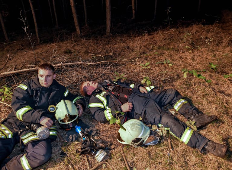 Im Kampf gegen die Flammen gehen die Feuerwehrleute an ihre Grenzen. Hier ruhen sich zwei Brandbekämpfer aus, bevor sie erneut gegen die Flammen kämpfen.