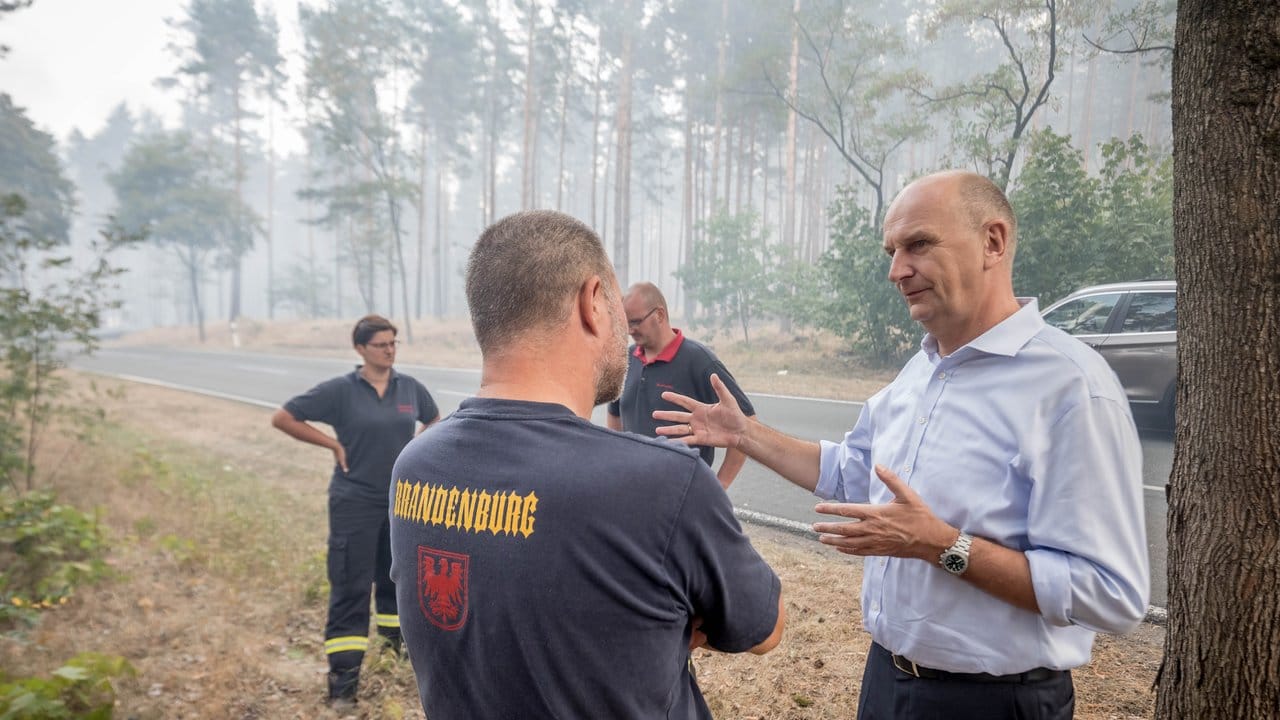 Dietmar Woidke, Ministerpräsident von Brandenburg, spricht mit Feuerwehrleuten im Wald. Dietmar Woidke, Ministerpräsident von Brandenburg, spricht mit Feuerwehrleuten im Wald.