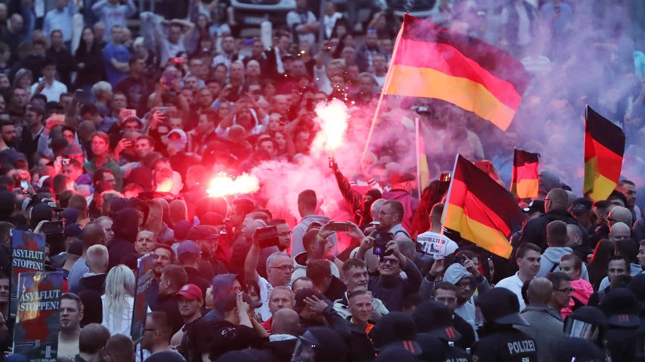 Demonstranten zünden Pyrotechnik und schwenken Deutschlandfahnen.