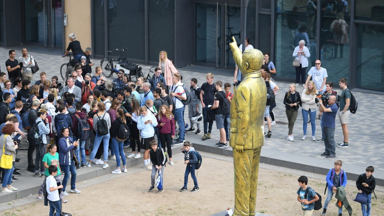 Neugierige Passanten haben sich in Wiesbaden an der goldenen Erdogan-Statue versammelt.