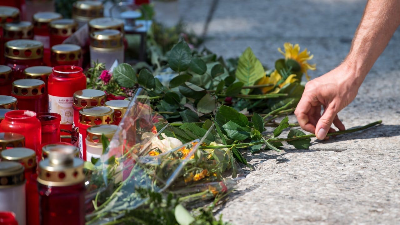 Ein Mann legt am Tatort in Chemnitz eine Blume nieder.