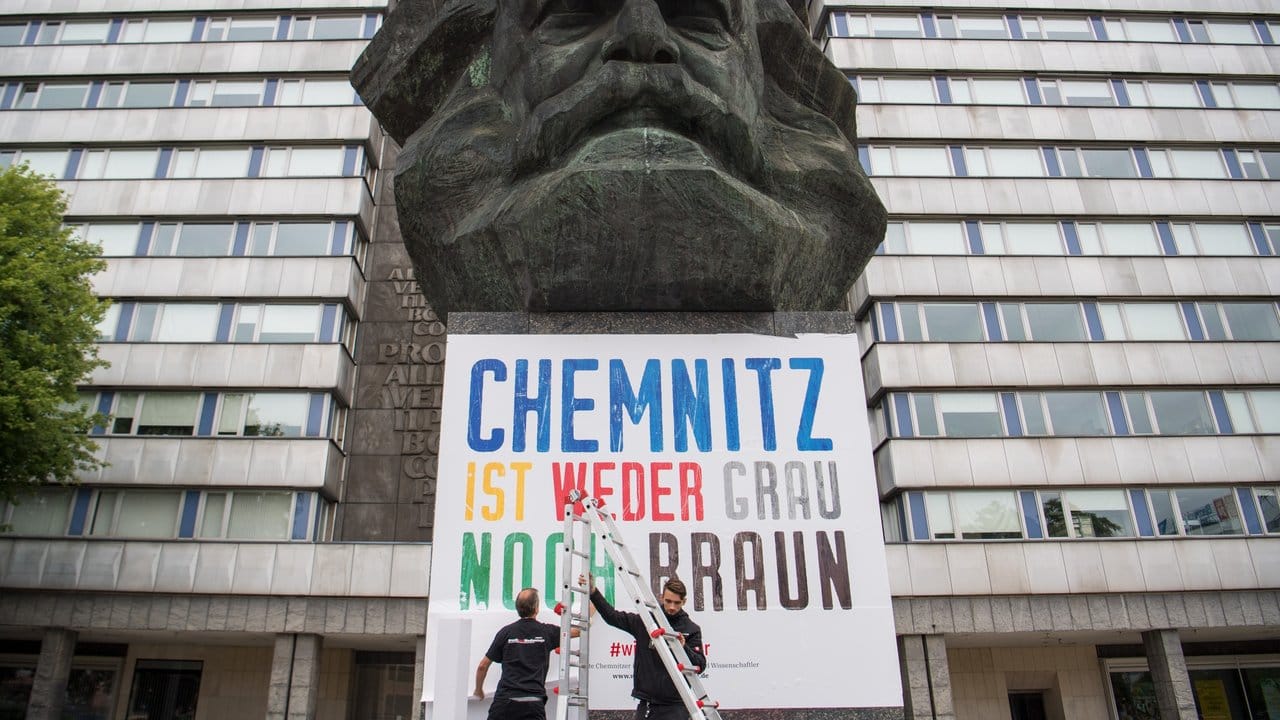 "Chemnitz ist weder grau noch braun": Zwei Männer befestigen am Karl-Marx-Denkmal in Chemnitz ein Plakat. "Chemnitz ist weder grau noch braun": Zwei Männer befestigen am Karl-Marx-Denkmal in Chemnitz ein Plakat.