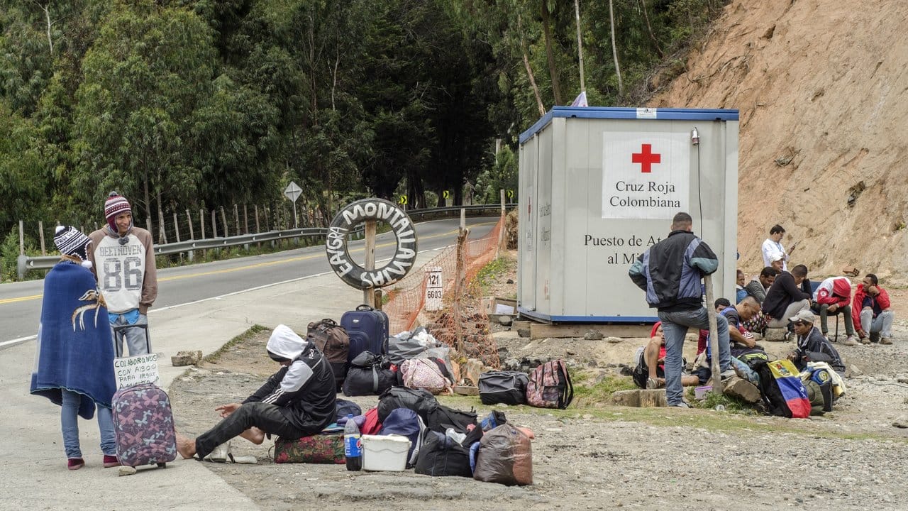 Eine Gruppe Migranten aus Venezuela wartet mit Koffern und Taschen vor einer Pflegestation des Roten Kreuzes.