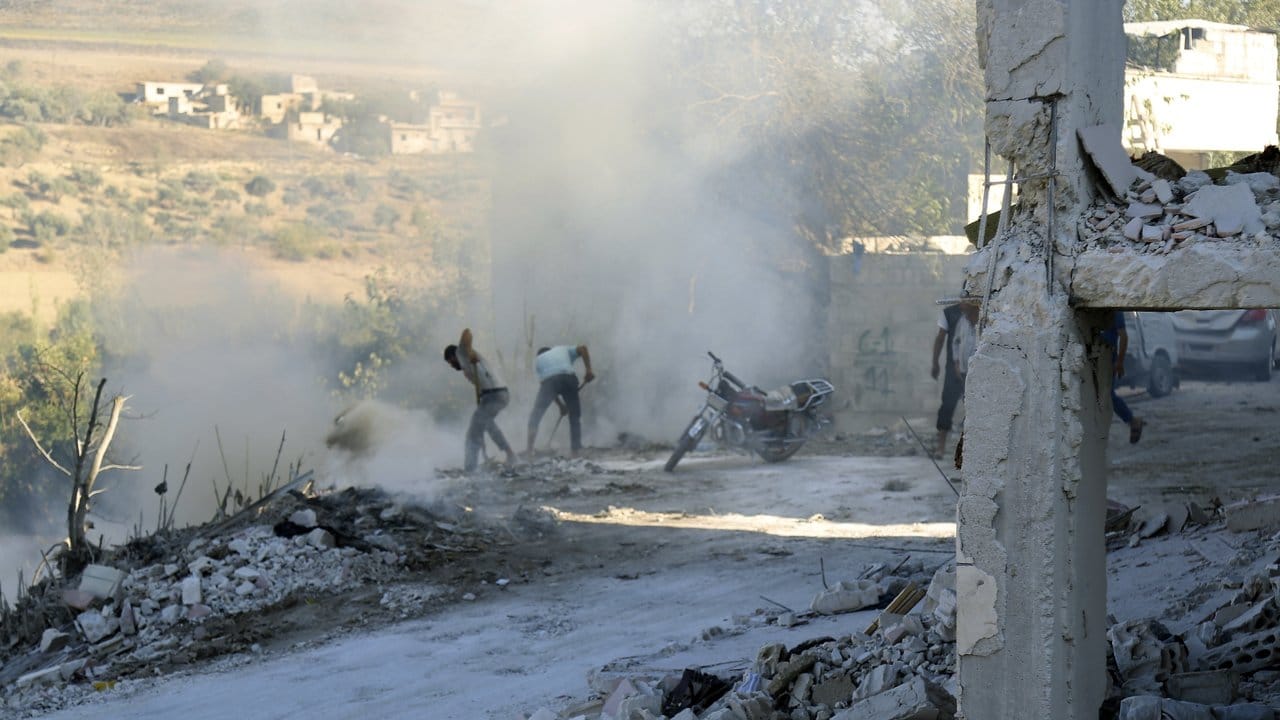 Syrer versuchen einen Brand nach einem Luftangriff im Bezirk Jisr al-Shughur in der Provinz Idlib zu löschen.