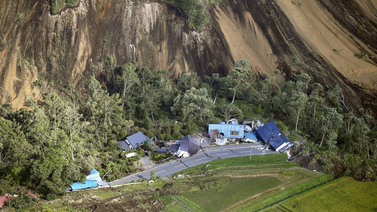 Zerstörte Häuser sind nach einem Erdbeben an der Stelle eines Erdrutsches neben einer Straße zu sehen.