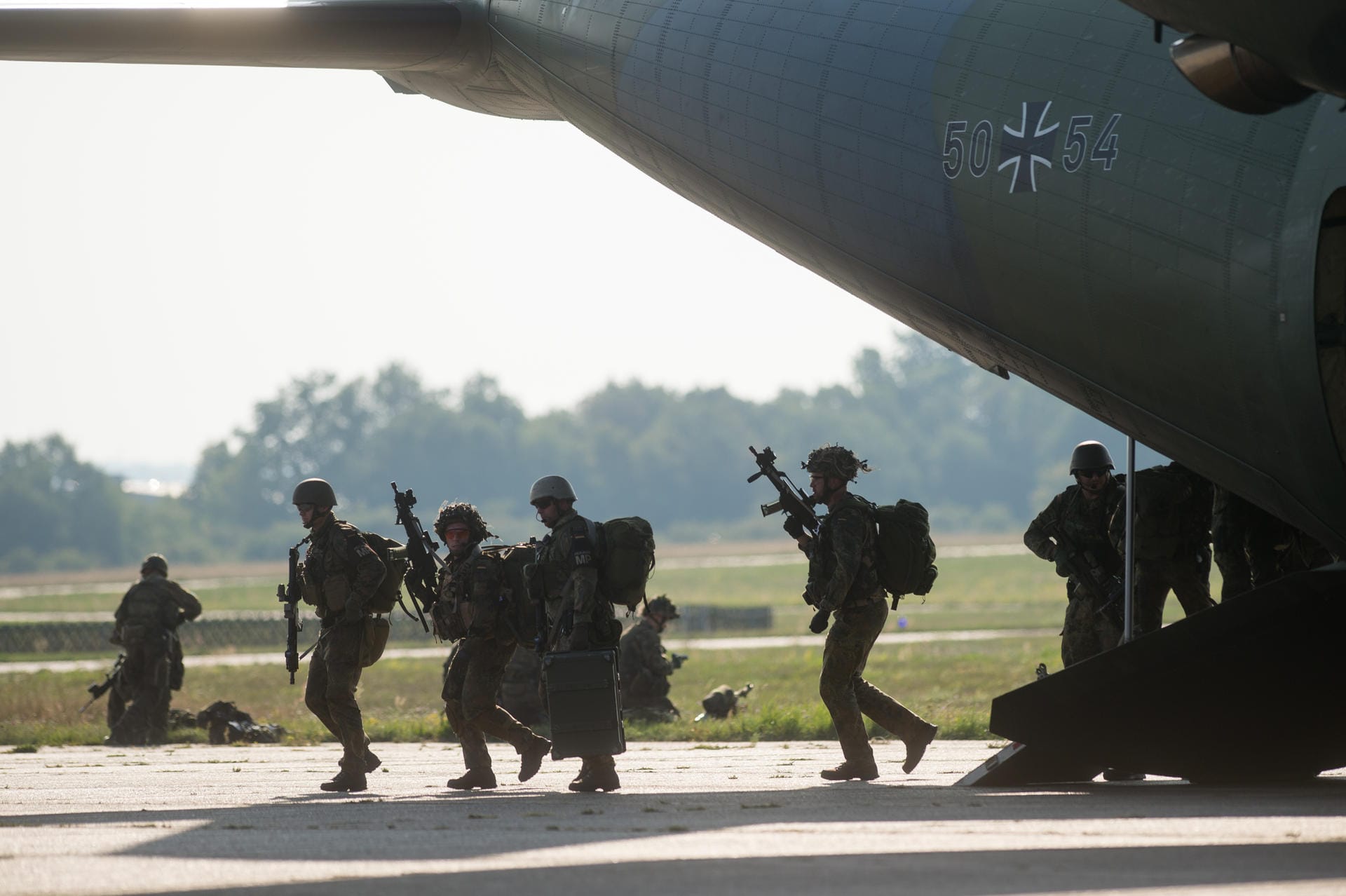 Fallschirmjäger verlassen auf dem Flugplatz eine Transall.