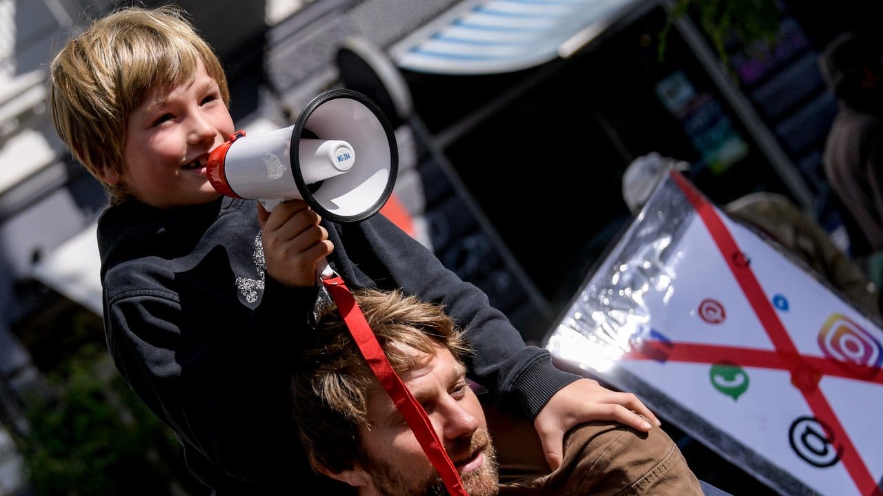 Auf den Schultern von Papa spricht der siebenjährige zu Demonstrationsteilnehmern. Auf den Schultern von Papa spricht der siebenjährige zu Demonstrationsteilnehmern.