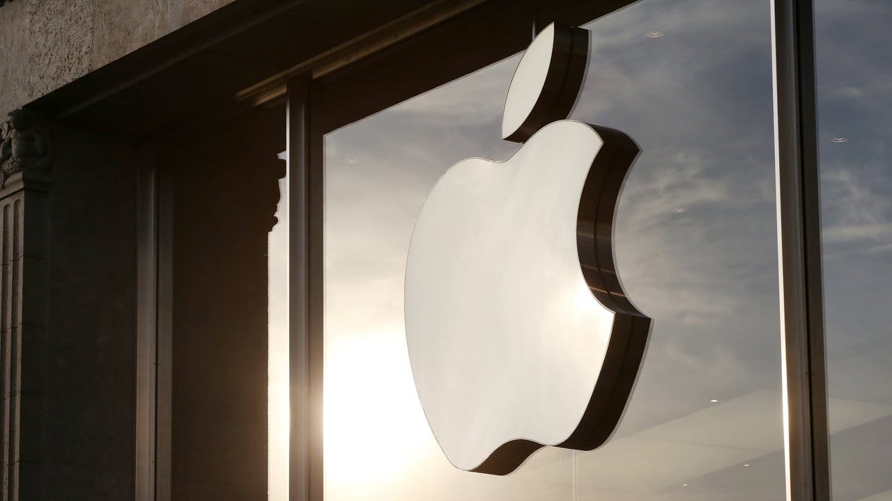 Die Sonne spiegelt sich neben dem Apple-Logo an der Fassade eines Apple-Stores.