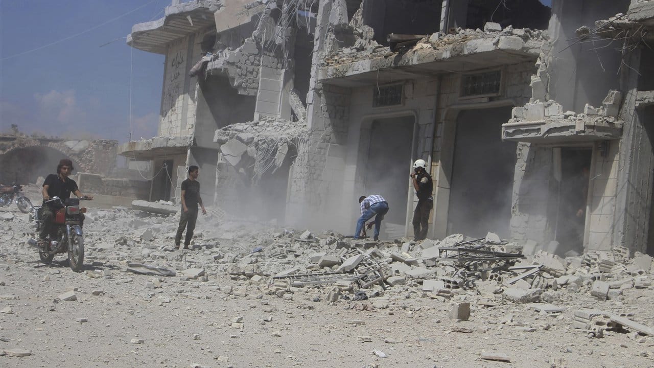 Zivilisten und Zivilschutzarbeiter neben einem Gebäude in Hobeit bei Idlib, das durch einen Luftangriff der syrischen Regierung zerstört wurde.