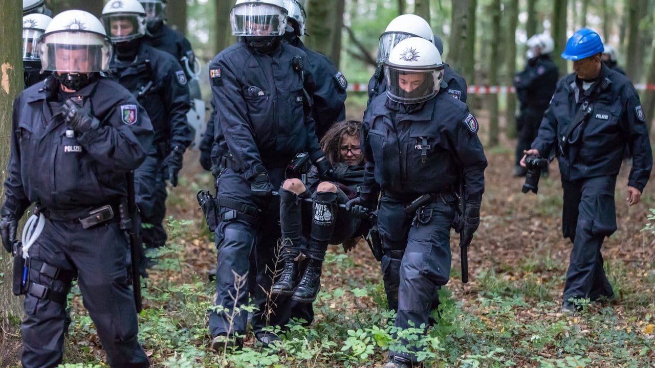 Polizisten tragen eine Umweltaktivistin weg.