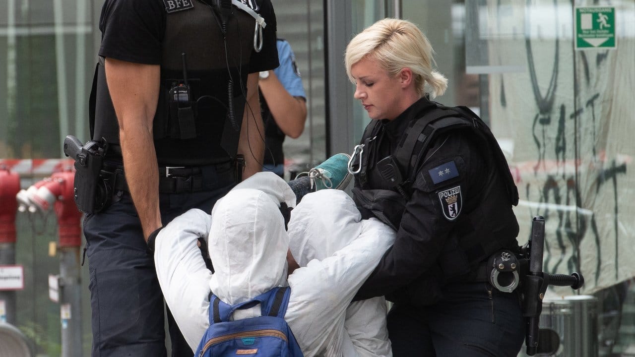 Polizeibeamte tragen einen Demonstranten aus der Landesvertretung von Nordrhein-Westfalen.