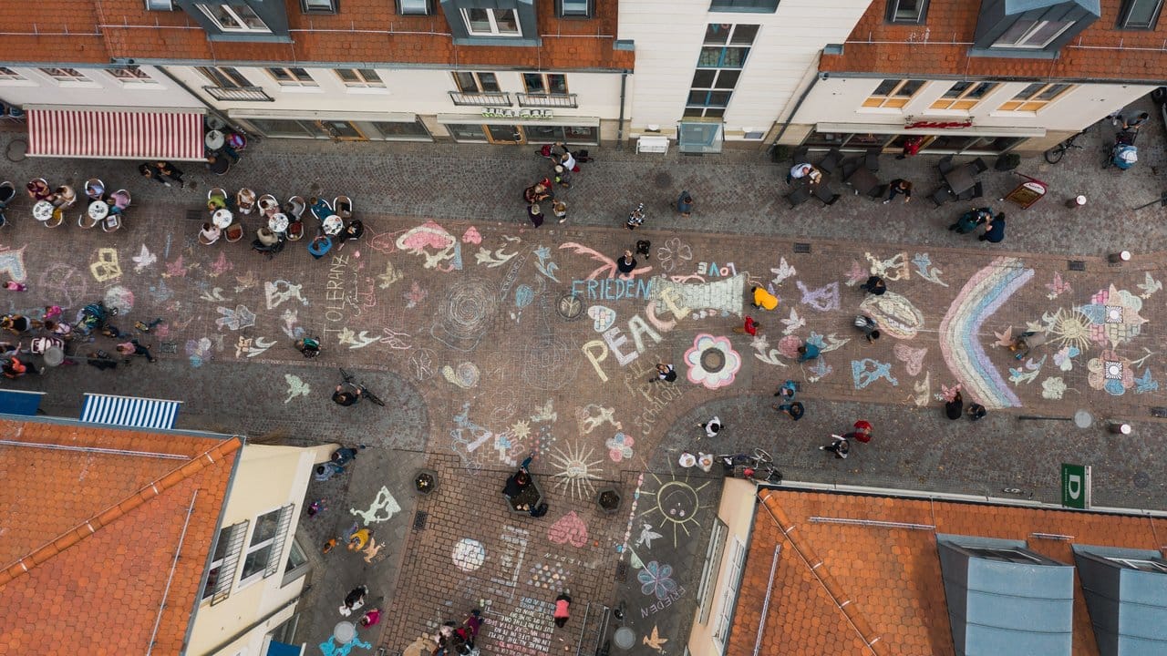 Mit Malkreide haben viele Bürgerinnen und Bürger Botschaften auf den Boden einer Straße in der Nähe des Marktplatzes gemalt und geschrieben. Mit Malkreide haben viele Bürgerinnen und Bürger Botschaften auf den Boden einer Straße in der Nähe des Marktplatzes gemalt und geschrieben.