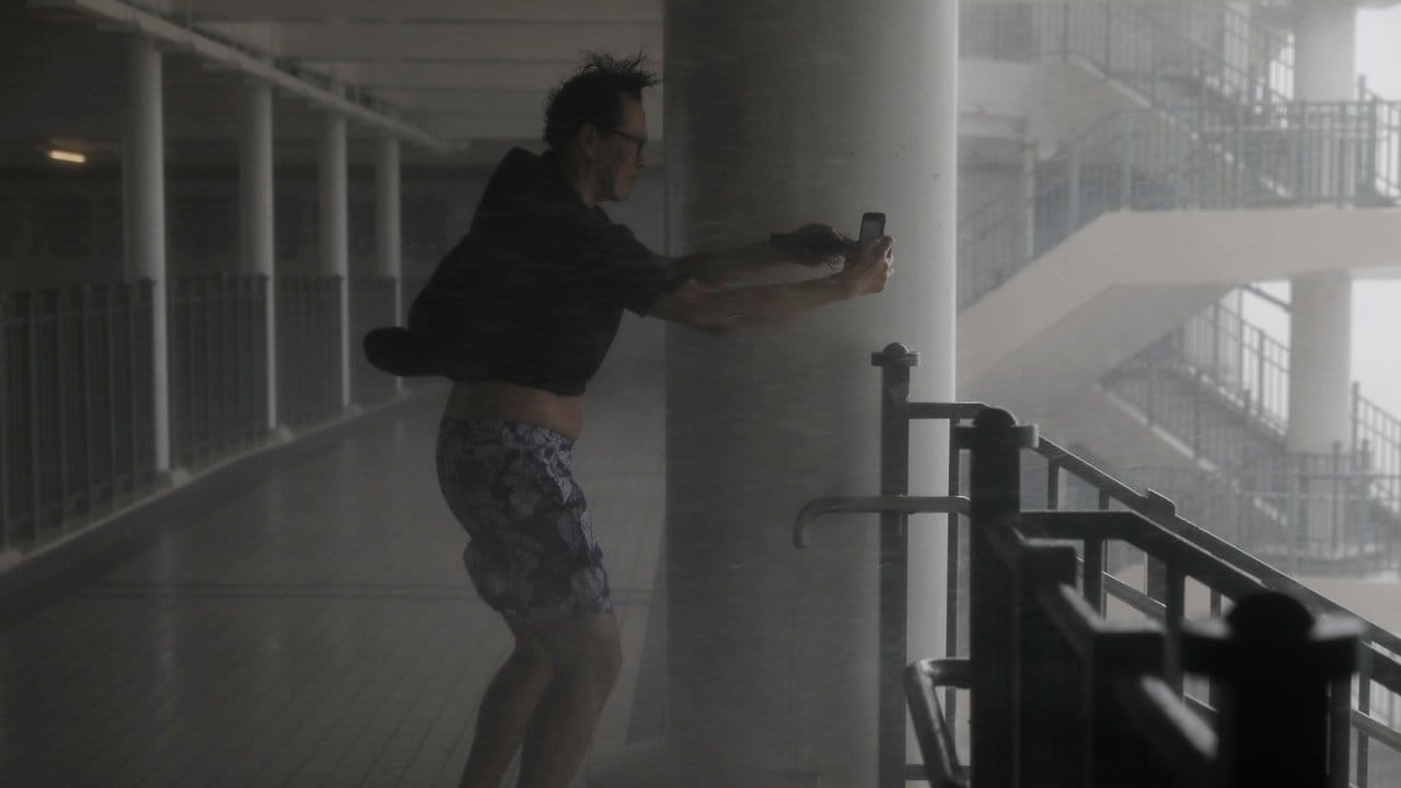 Sich gegen den Wind stemmend, versucht einMann in Hongkong Fotos zu machen.