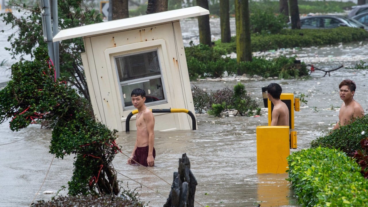 Jugendliche waten durch eine überflutete Straße in Hongkong.