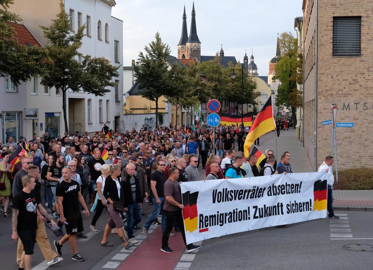 Teilnehmer der Demonstration von rechtsgerichteten Bündnissen ziehen mit einem Transparent "Volksverräter absetzen! Remigration! Zukunft sichern!" durch die Stadt.