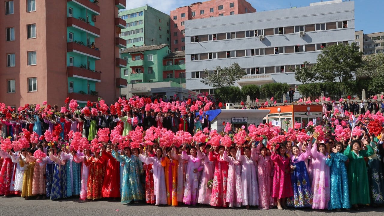 Frauen in volkstümlichen Gewändern säumen eine Straße in Pjöngjang.