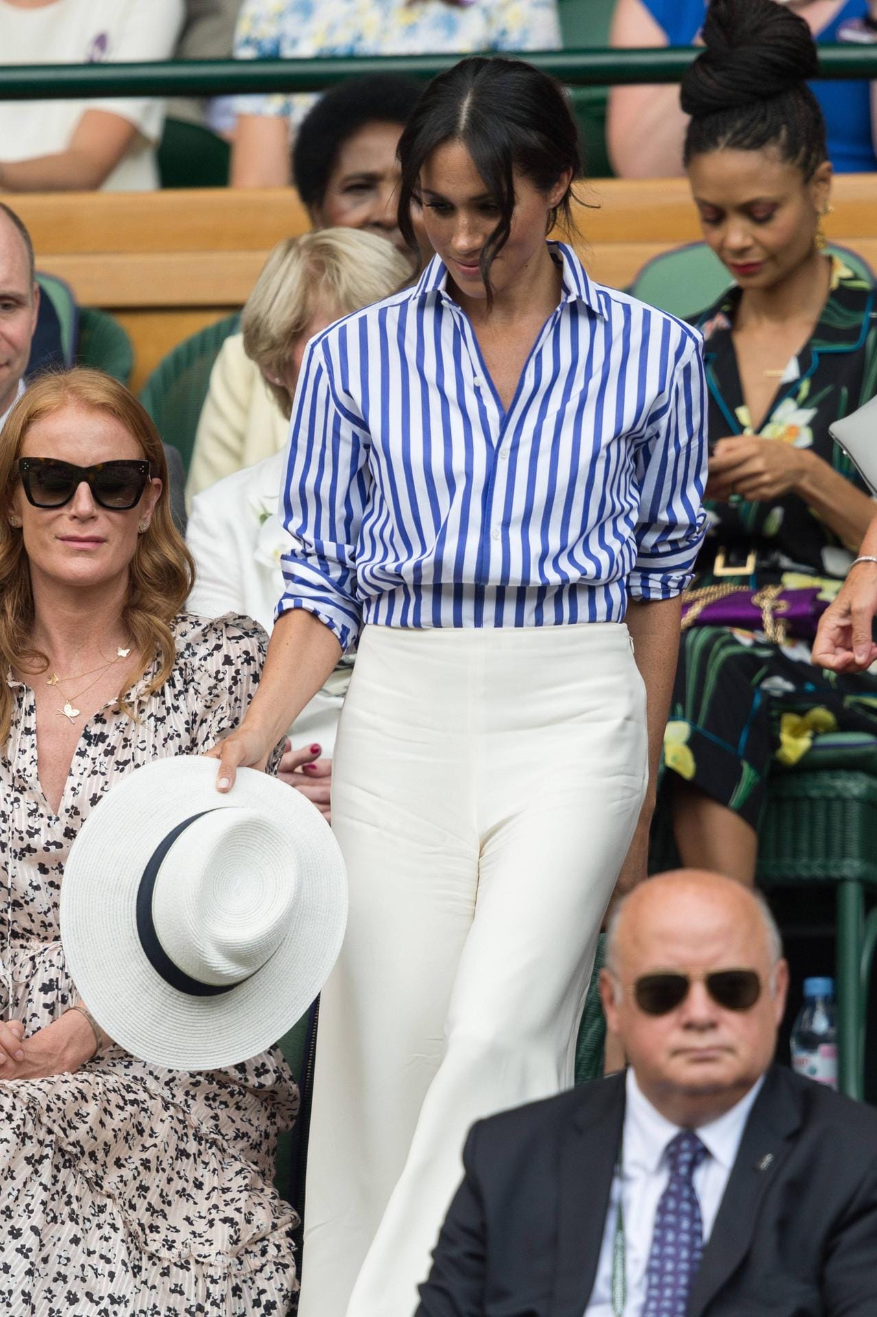 Hätte sie auch als Meghan Markle schon getragen: Die Herzogin in lässiger Streifenbluse, weißer Palazzo-Hose und mit weißem Hut beim Tennisspiel in Wimbledon im Juli 2018. Bei diesem Freizeitlook durfte auch der lockere Dutt nicht fehlen.