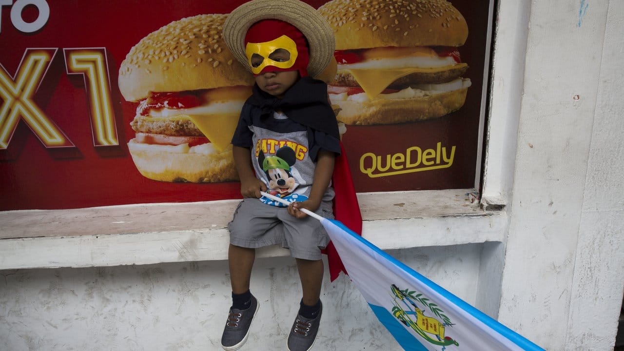 Ausgestattet mit Kostüm und Landesfahne wartet ein Junge auf den Beginn der Demonstration in Guatemala-Stadt.