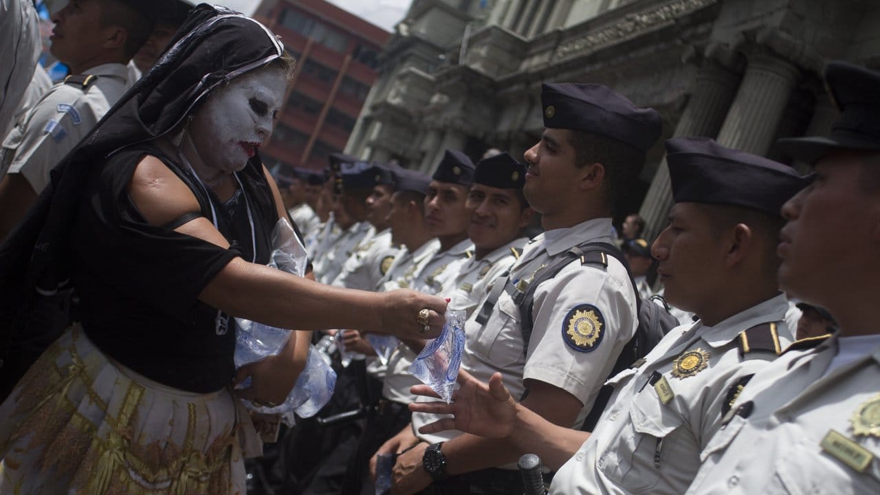 Eine Demonstrantin gibt Polizisten während eines Protests auf dem Platz der Verfassung Plastiktüten mit Wasser.