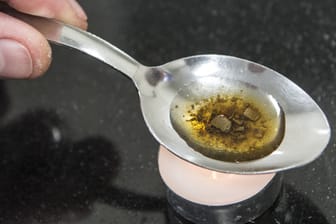 Ein Mann "kocht" auf einem Löffel die Dosis für einen Schuss Heroin: Nach einem Bericht der Weltkommission für Drogenpolitik konsumieren weltweit rund 250 Millionen Menschen illegale Drogen.