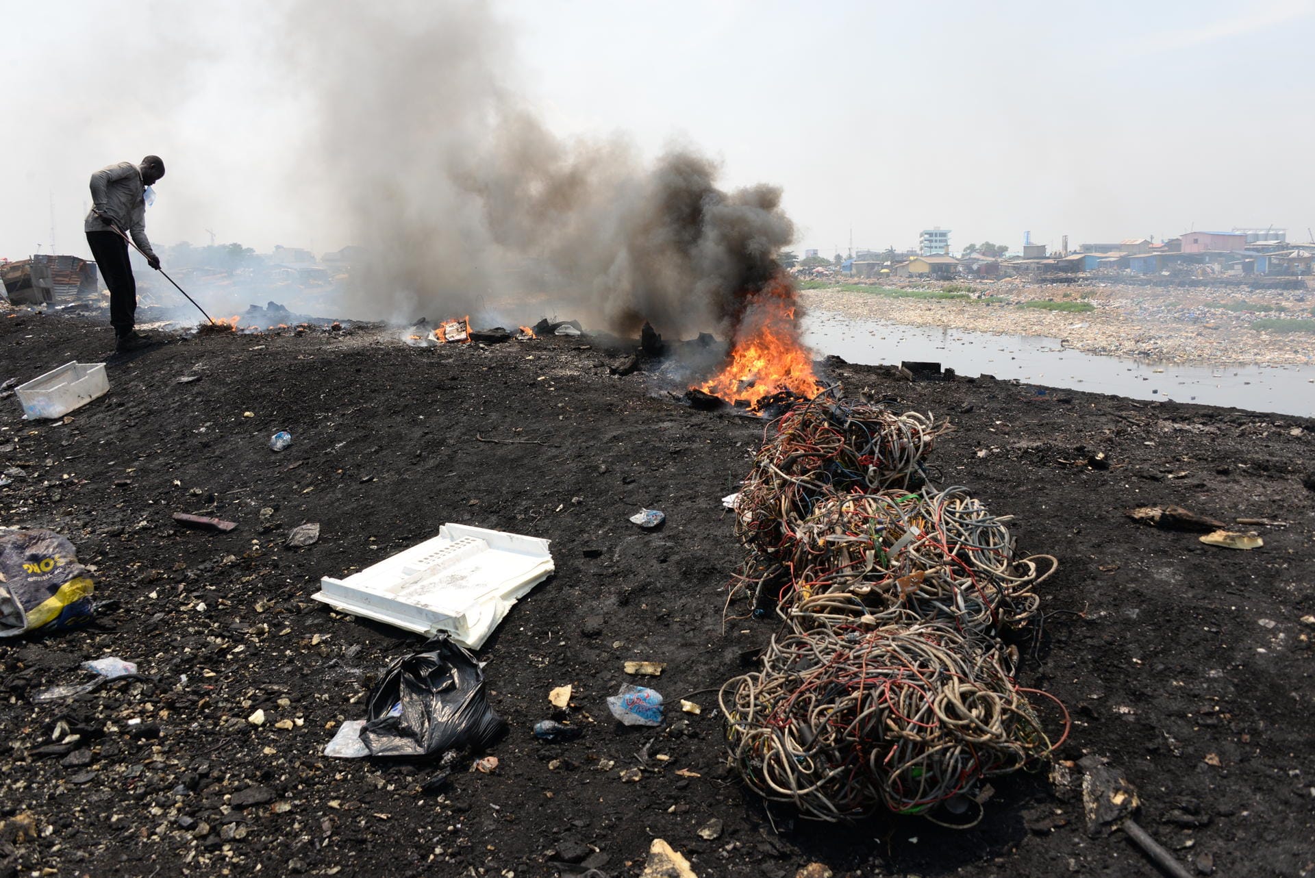 Männer verbrennen auf dem Schrottplatz Agbogbloshie Kabel und andere Teile alter Elektrogeräte.