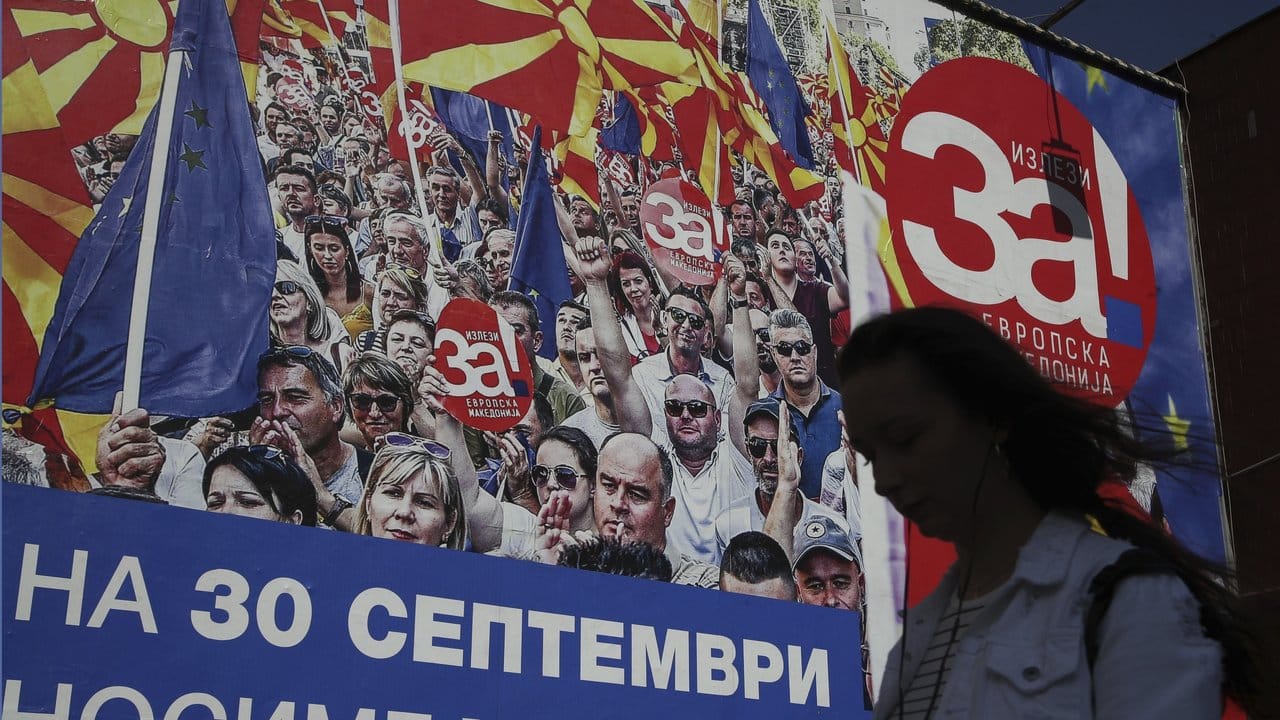 Eine Frau geht in Skopje an einem Banner mit der Aufschrift "Für ein europäisches Mazedonien - Am 30. Eine Frau geht in Skopje an einem Banner mit der Aufschrift "Für ein europäisches Mazedonien - Am 30.