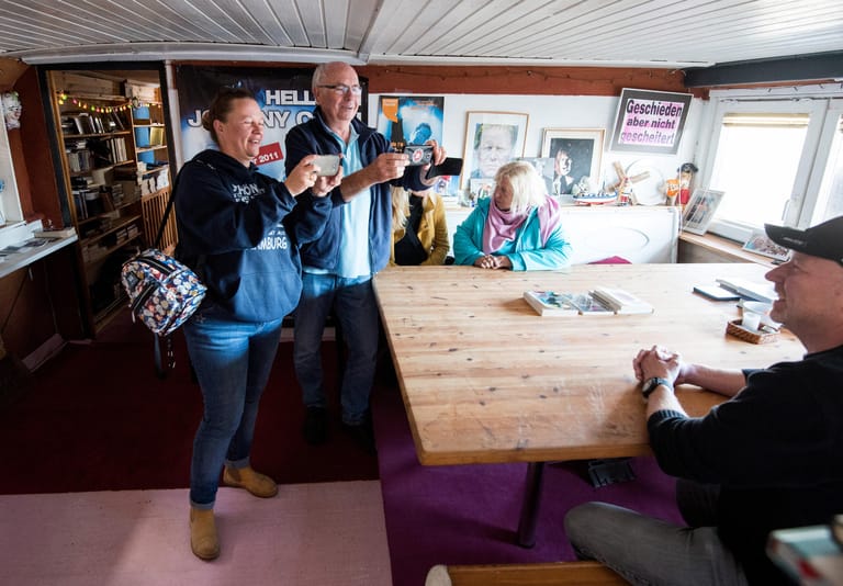 Besucher fotografieren sich auf dem Hausboot von Gunter Gabriel am Esstisch.