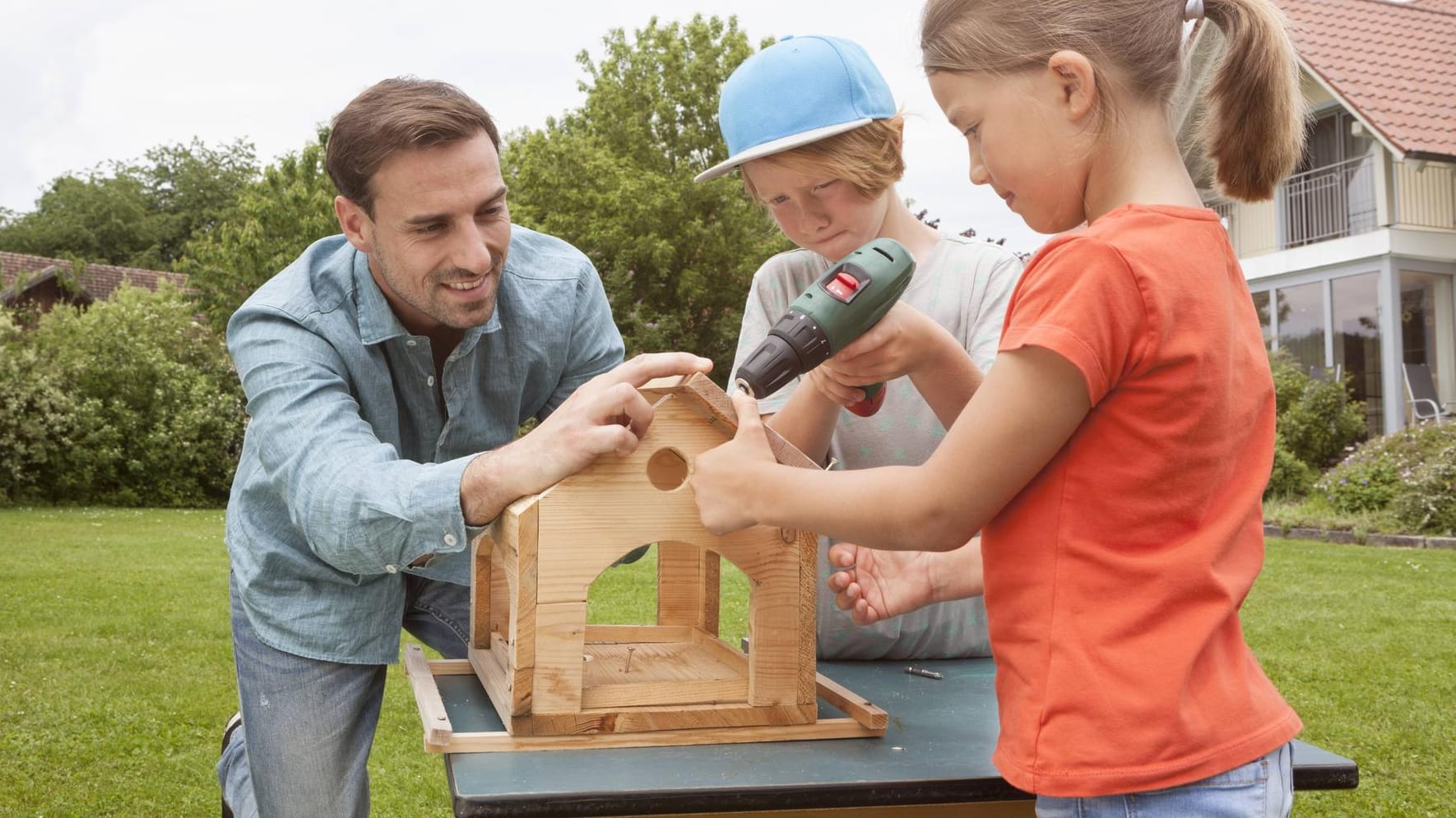 Vater baut Vogelhaus mit Kindern