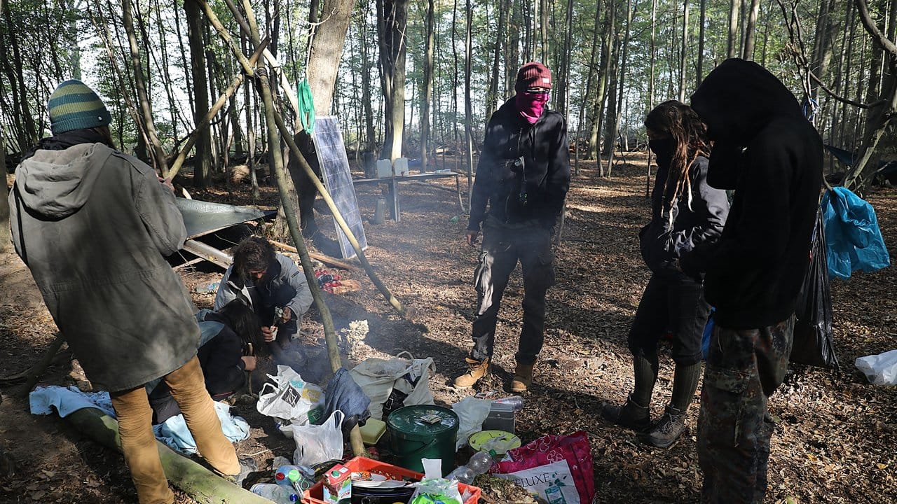 Aktivisten stehen im Hambacher Forst an einer Feuerstelle.