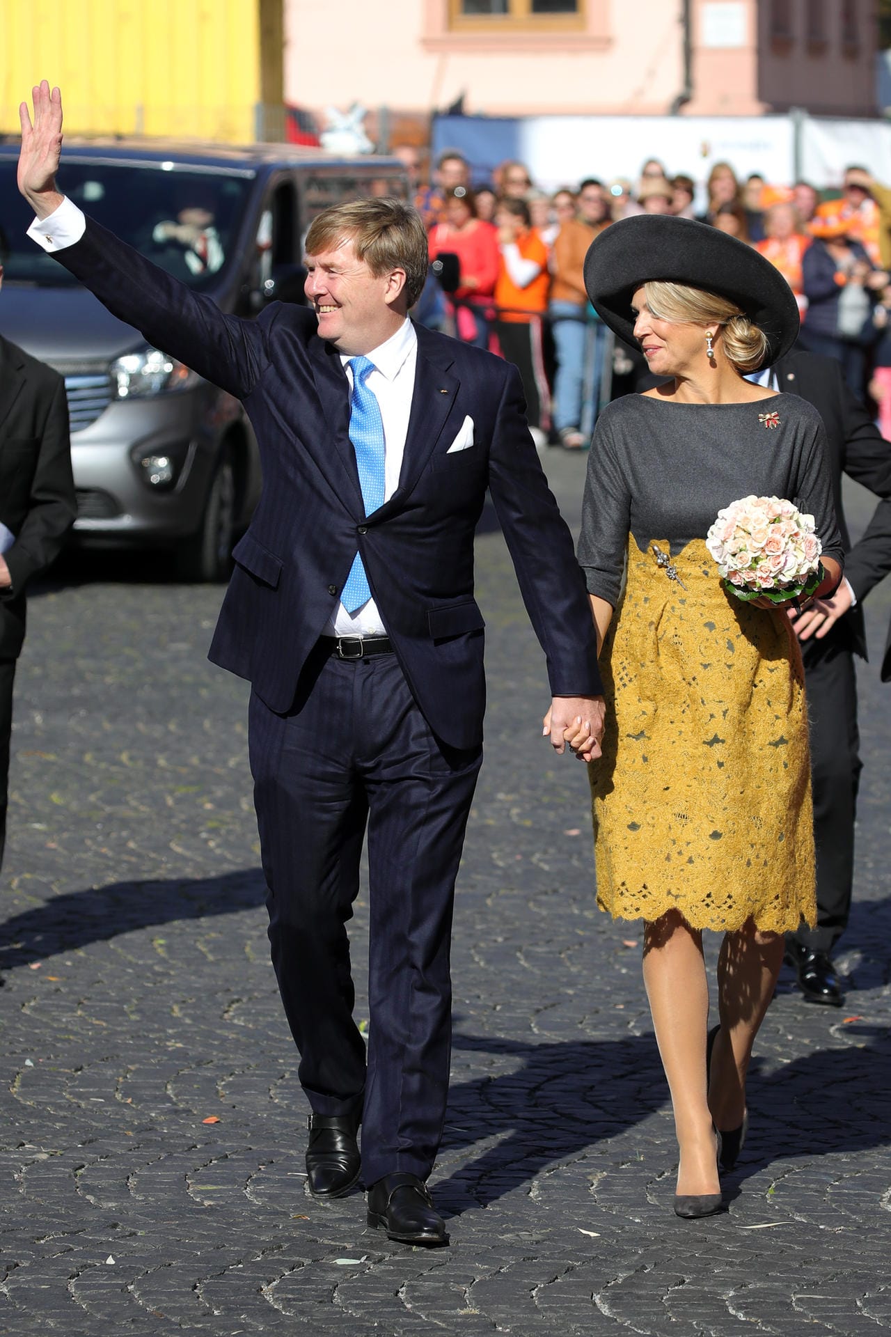 Hand in Hand: Willem-Alexander winkt der Menge zu, seine Ehefrau begeistert in einem Kostüm mit senfgelbem Rock von Natan.