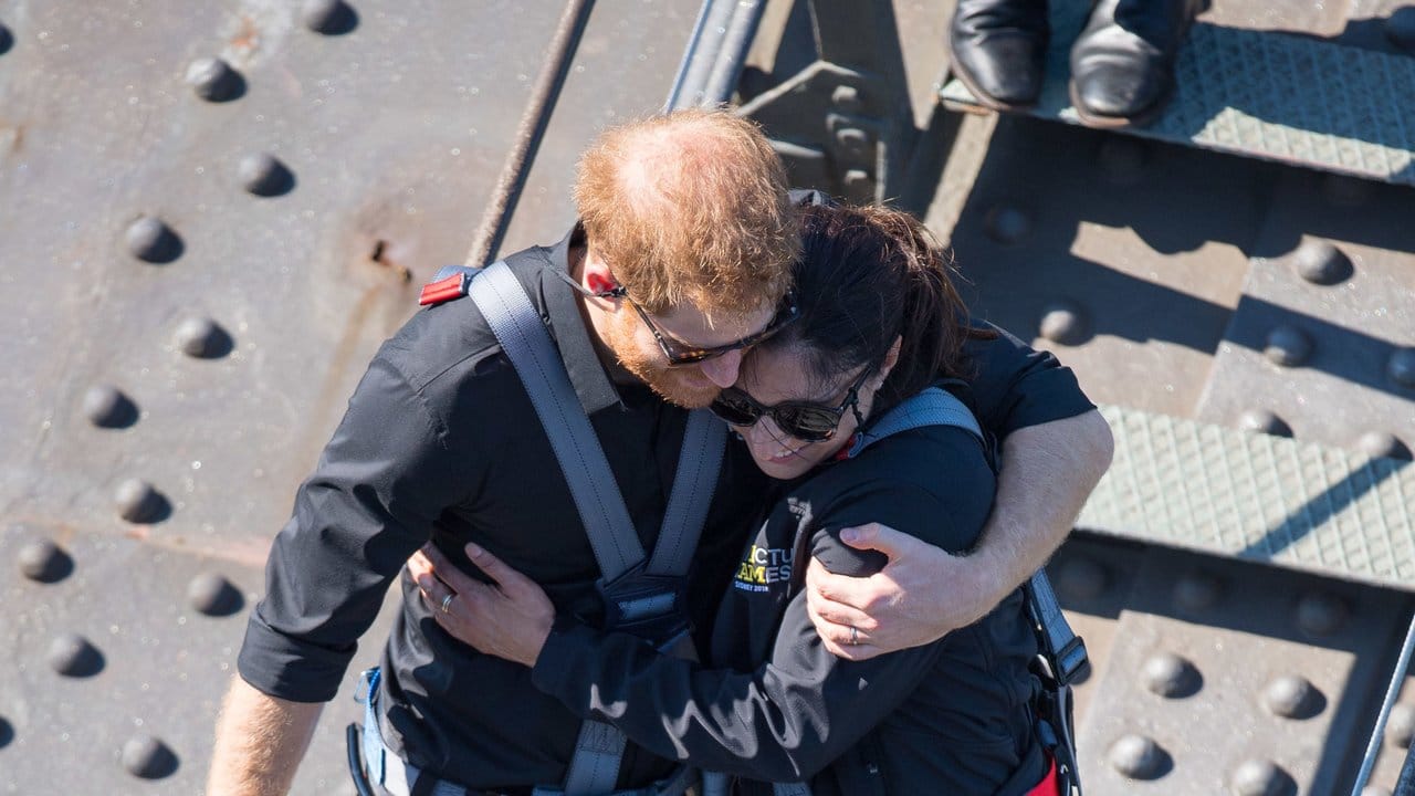 Prinz Harry umarmt eine Teilnehmerin der Invictus Games, als sie die Sydney Harbour Bridge besteigen.