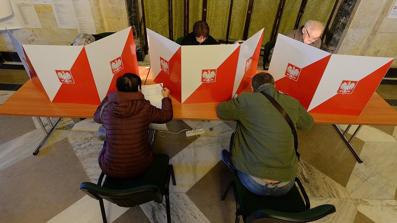 Menschen geben in einem Wahllokal in Warschau ihre Stimme ab.