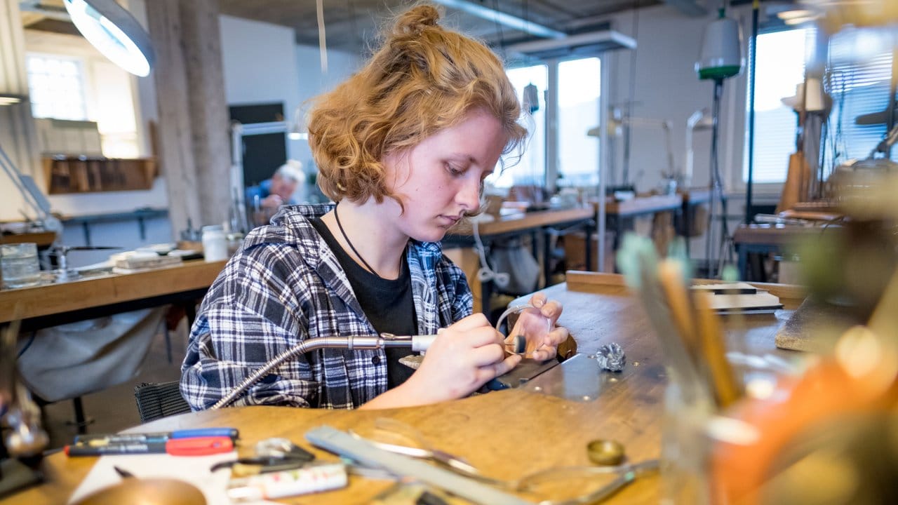 Die angehende Goldschmiedin Gwendolin Proksch poliert einen Armreif aus Silber in der Werkstatt ihres Ausbildungsbetriebs in Hannover.
