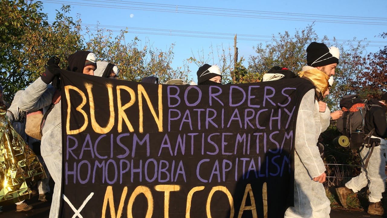 Umweltaktivisten tragen Banner mit dem Aufschrift: "Burn Borders, Patriarchy, Racism, Antisemitism, Homophobia, Capitalism, Not Coal".